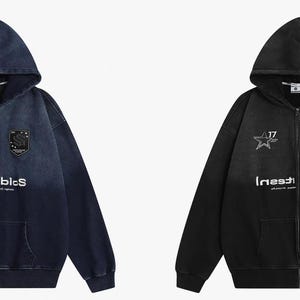 May include: Two zip-up hoodies, one in a dark blue denim wash and the other in black. Each features a hood, front pockets, and a white graphic that reads "Inestublcs" with a star and shield emblem. The number "17" is also visible.