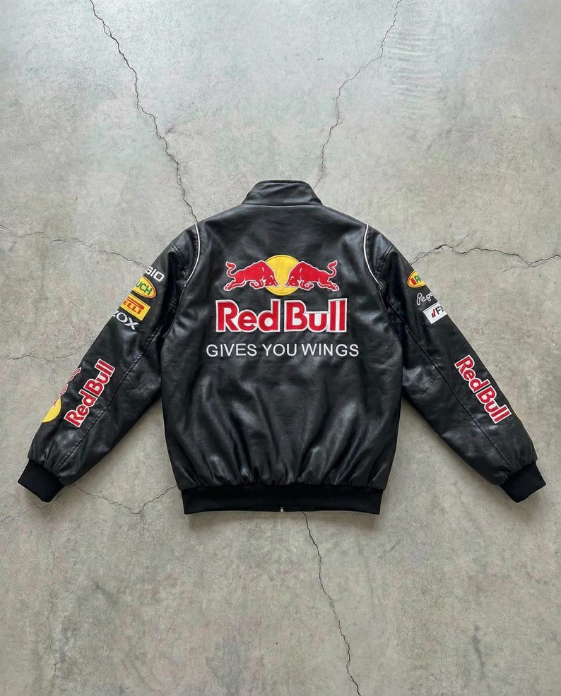 May include: Black leather jacket with Red Bull logos and text. The jacket features white trim, black cuffs, and the phrase "GIVES YOU WINGS" on the back. Logos are on the sleeves and chest.