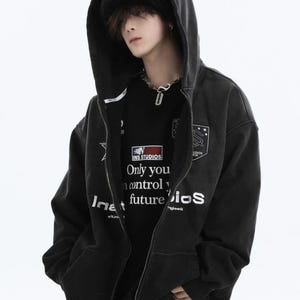 May include: Black zip-up hoodie with a hood and a black beanie. The hoodie has white text and a patch on the chest. The black t-shirt underneath has the text "INS STUDIOS Only you control your future iOS".