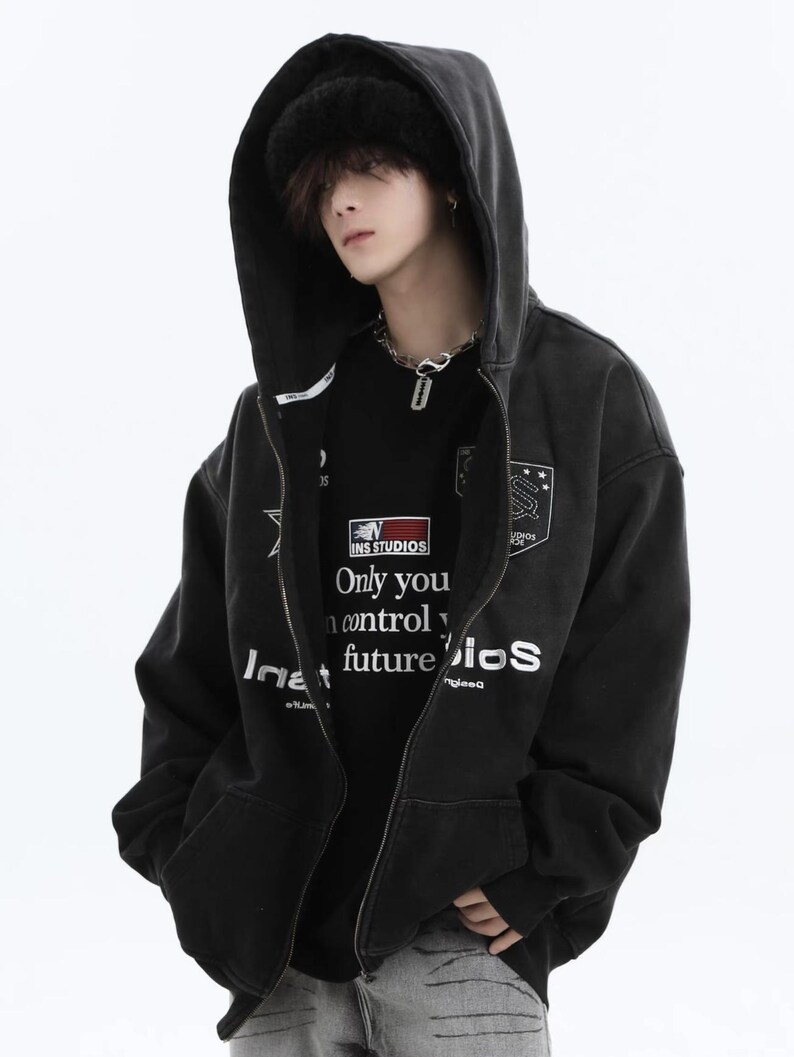 May include: Black zip-up hoodie with a hood and a black beanie. The hoodie has white text and a patch on the chest. The black t-shirt underneath has the text "INS STUDIOS Only you control your future iOS".