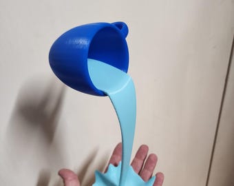 Puede incluir: Una taza de té azul parece estar vertiendo un líquido azul claro en un chapoteo estilizado. La taza de té tiene un asa y está inclinada, con el líquido fluyendo hacia abajo. El chapoteo se sostiene en una mano.