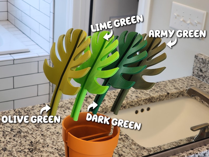 Peut inclure: Quatre accessoires de salle de bain d&eacute;coratifs en forme de feuilles, de couleur vert olive, vert citron, vert fonc&eacute; et vert arm&eacute;e, pr&eacute;sent&eacute;s dans un support orange. Les feuilles sont en mat&eacute;riau solide.