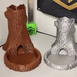 Puede incluir: Dos torres de dados impresas en 3D con forma de tocones de árbol. Una es marrón y la otra es plateada.