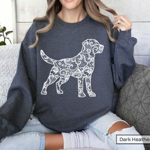 May include: Dark heather gray sweatshirt featuring a white lace-patterned dog silhouette. The dog design is detailed and stands out against the dark background. The sweatshirt is a casual style, suitable for everyday wear.
