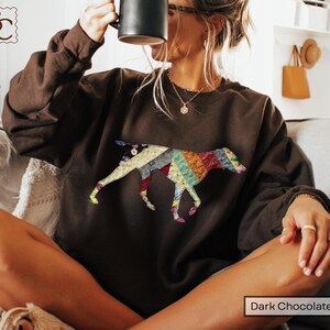 May include: Dark chocolate brown sweatshirt with a patchwork dog design. The dog silhouette is made up of various fabric patterns and colours, including red, blue, yellow, and green. The text "Dark Chocolate" is at the bottom.