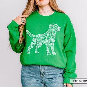 May include: A bright green sweatshirt featuring a white lace-patterned dog silhouette. The sweatshirt has long sleeves and a crew neck. The text "Irish Green" is visible in the bottom right corner.