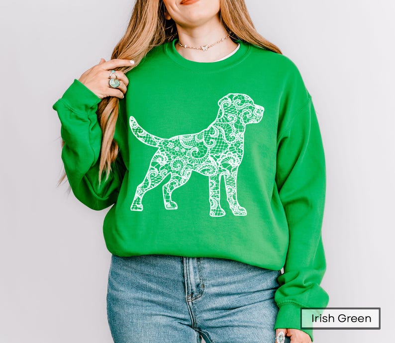 May include: A bright green sweatshirt featuring a white lace-patterned dog silhouette. The sweatshirt has long sleeves and a crew neck. The text "Irish Green" is visible in the bottom right corner.