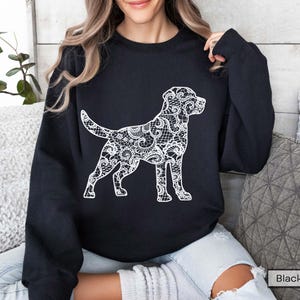 May include: Black sweatshirt featuring a white dog silhouette with a lace-like design. The dog is in a standing pose, with its tail up. The sweatshirt is a solid black color.