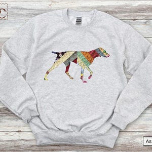 May include: Light grey sweatshirt with a patchwork dog design. The dog is made up of colourful fabric patterns in red, green, yellow, and blue. A comfortable, casual top for dog lovers.