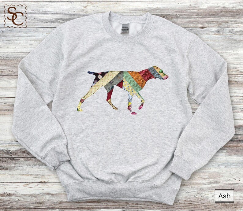 May include: Light grey sweatshirt with a patchwork dog design. The dog is made up of colourful fabric patterns in red, green, yellow, and blue. A comfortable, casual top for dog lovers.