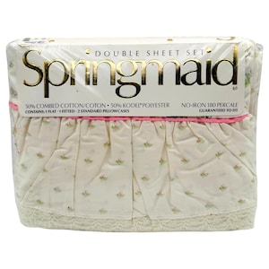 May include: A Springmaid double sheet set in original plastic packaging. The set includes one flat sheet, one fitted sheet, and two standard pillowcases. The fabric is cream-colored with a small pink floral pattern, a pink trim, and lace.