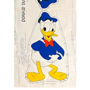 May include: A vintage sewing pattern for a Donald Duck plush toy. The pattern includes instructions for cutting out the fabric and sewing the pieces together. The pattern is printed on white fabric with blue and yellow accents.