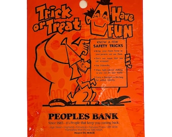 Könnte beinhalten: Orangefarbener Plastik-Trick-or-Treat-Beutel mit einem Comic-Clown, der ein Schild mit der Aufschrift "Know a Few Safety Tricks" hält. Der Beutel ist von der Peoples Bank und enthält deren Logo und Kontaktinformationen.