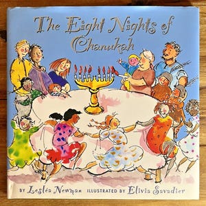 Könnte beinhalten: Kinderbuchcover mit dem Titel "The Eight Nights of Chanukah", das eine Familie beim Feiern des Feiertags zeigt. Das Cover zeigt eine Menora mit brennenden Kerzen, einen Tisch und tanzende Kinder. Autorin ist Lesléa Newman, Illustratorin Elivia Savadier.