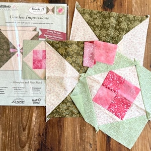 Puede incluir: Un kit Quilt Blocks Collection Garden Impressions Block 11 en una funda de plástico, con formas de tela precortadas e instrucciones. Al lado hay dos bloques de edredón de tela parcialmente ensamblados en tonos oliva, crema y rosa.