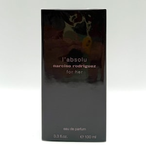 Może przedstawiać: Ciemne, prostokątne pudełko perfum z napisem "l'absolu narciso rodriguez for her". Na pudełku widnieją słowa "eau de parfum", "3.3 fl.oz." i "e 100 ml".