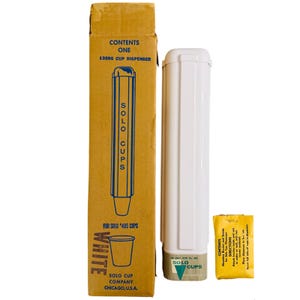 Puede incluir: Un juego de dispensador de vasos Solo vintage, que incluye un dispensador de plástico blanco, una caja de cartón y un pequeño paquete amarillo. La caja es de color canela con texto azul y blanco, y el dispensador es blanco con un logotipo verde de Solo Cups.