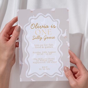 May include: A light gray invitation with a whimsical design, featuring the text "Olivia is ONE Silly Goose." The invitation includes event details and is decorated with small goose illustrations.