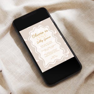 May include: A smartphone displays a birthday invitation. The invitation features the text "Olivia is ONE Silly Goose" in gold script, with a beige background and goose illustrations. The phone is black.