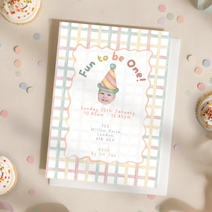 May include: A pastel-colored invitation card with the text "Fun to be One!" and a baby wearing a party hat. The card includes event details: date, time, and address. The design features a plaid pattern and a scalloped border.