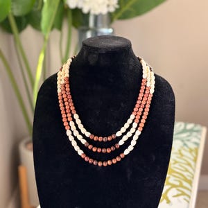 Puede incluir: Una taza de cerámica blanca con un asa negra y el texto "But First, Coffee" en negro en negrita. La taza está sobre una superficie blanca.