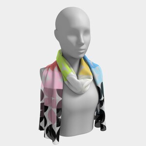 May include: A colourful scarf with a geometric pattern of circles in shades of pink, black, white, yellow, green, and blue. The scarf is worn around the neck of a mannequin.