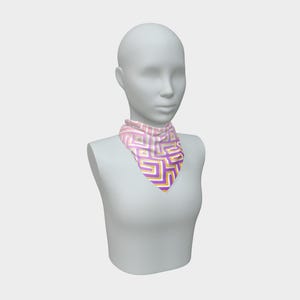 May include: A pink, white, yellow, and purple geometric patterned scarf is displayed on a mannequin. The scarf is square-shaped and folded in a triangle, with the point facing down. The pattern is a repeating design of interlocking shapes.