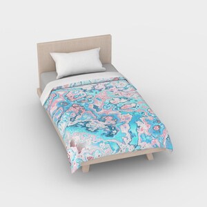 May include: A twin-sized bed with a light blue and pink abstract patterned duvet cover. The duvet cover has a swirling, marbled design.