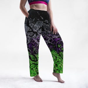 May include: Black, grey, purple, and green patterned pants. The pants feature a unique design with a gradient effect, transitioning from black at the top to green at the bottom. The pattern includes abstract shapes and swirls.