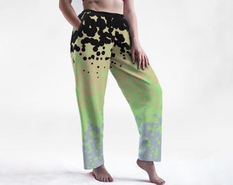May include: Loose-fitting, patterned pants with a unique design. The pants feature a color gradient, transitioning from a tan base to green and gray at the bottom. Black circular shapes are scattered across the top. The pants have pockets.