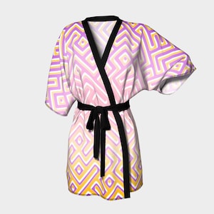 May include: A patterned robe in shades of pink, yellow, and purple with a black belt and trim. The robe features a geometric design and a wrap-around style. The robe is made of a soft, flowing fabric.