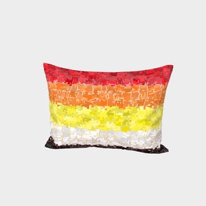 Peut inclure: Coussin rectangulaire décoratif avec un motif abstrait vibrant. Il présente des bandes horizontales de couleurs, allant du rouge en haut, en passant par l'orange et le jaune, jusqu'au blanc en bas. Le design a un aspect texturé et pixélisé.