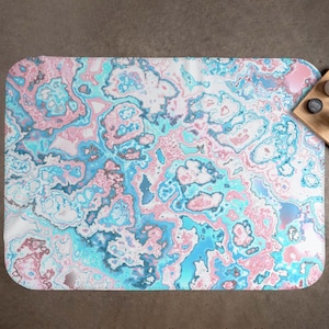 May include: Abstract area rug with a swirling pattern of pink, blue, and white. The rug has a modern and contemporary design.