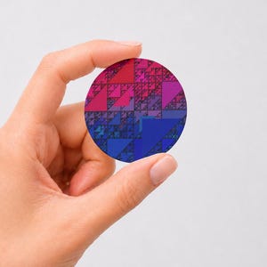 May include: A circular pin featuring a fractal pattern of triangles in a gradient of colors transitioning from magenta and pink at the top to purple in the center and deep blue at the bottom, creating a geometric and repeating visual design.