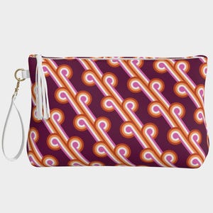 May include: A rectangular clutch bag with a retro pattern of diagonal lines in white, orange, and pink on a deep purple background. It has a white tassel zipper pull and a white wrist strap with gold hardware.