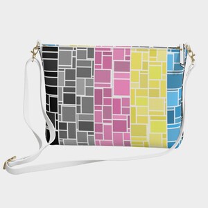 May include: A rectangular crossbody bag with a vibrant geometric design. The bag has a white adjustable strap and gold-tone hardware. The pattern features rectangular shapes in black, grey, pink, yellow, and blue.