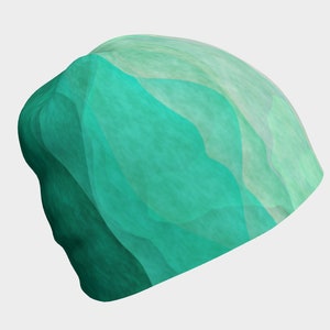 May include: A beanie hat with a wavy, abstract design. The hat features shades of teal and light green, creating a layered, textured appearance. The hat is made of a soft material.