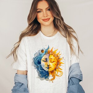May include: A white t-shirt with a watercolor illustration of a sun and moon with closed eyes. The sun is yellow and orange, and the moon is blue and white.