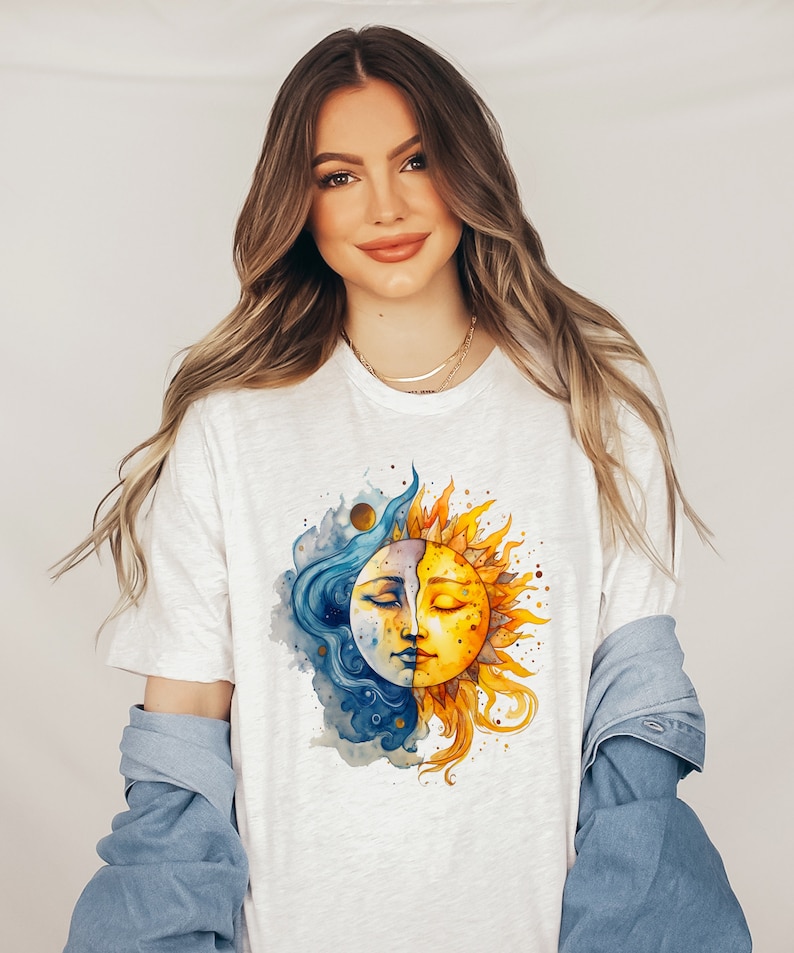 May include: A white t-shirt with a watercolor illustration of a sun and moon with closed eyes. The sun is yellow and orange, and the moon is blue and white.