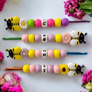 May include: Four colorful crochet hooks with bee and flower charms. Each hook has a letter bead, spelling out the word "C-G-H-I".