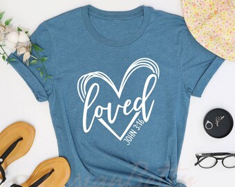 May include: A heather deep teal t-shirt with a white graphic of a heart with the word "loved" and the text "John 3:16" inside the heart.