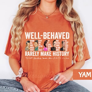 May include: Orange t-shirt with a white graphic print featuring portraits of notable women and the text "Well-Behaved Rarely Make History". The text includes quotes from each woman.