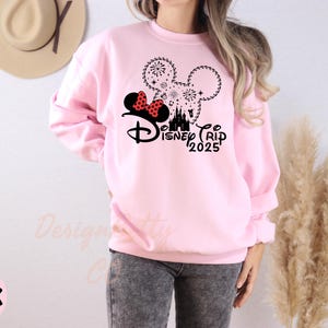a woman wearing a pink sweatshirt with minnie mouse on it