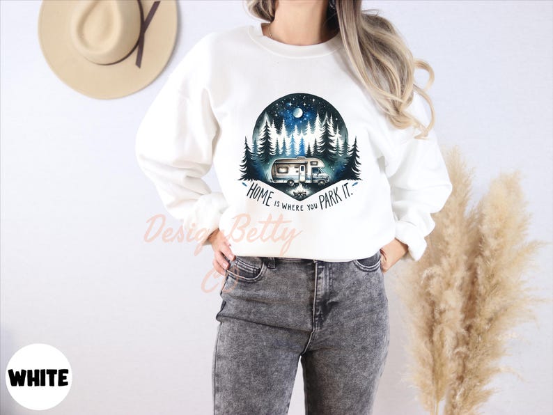 May include: White sweatshirt with a graphic of a camper van in a forest at night. The text "Home is where you park it." is printed on the sweatshirt.