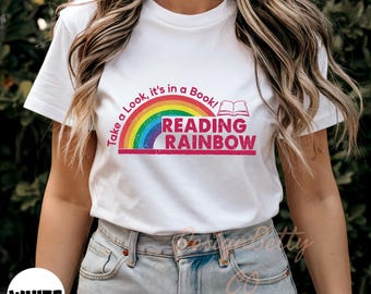 May include: White t-shirt with a rainbow and the text "Take a look, it's in a book! Reading Rainbow" in pink.