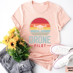 a t - shirt that says drone pilot next to a bouquet of sunflowers