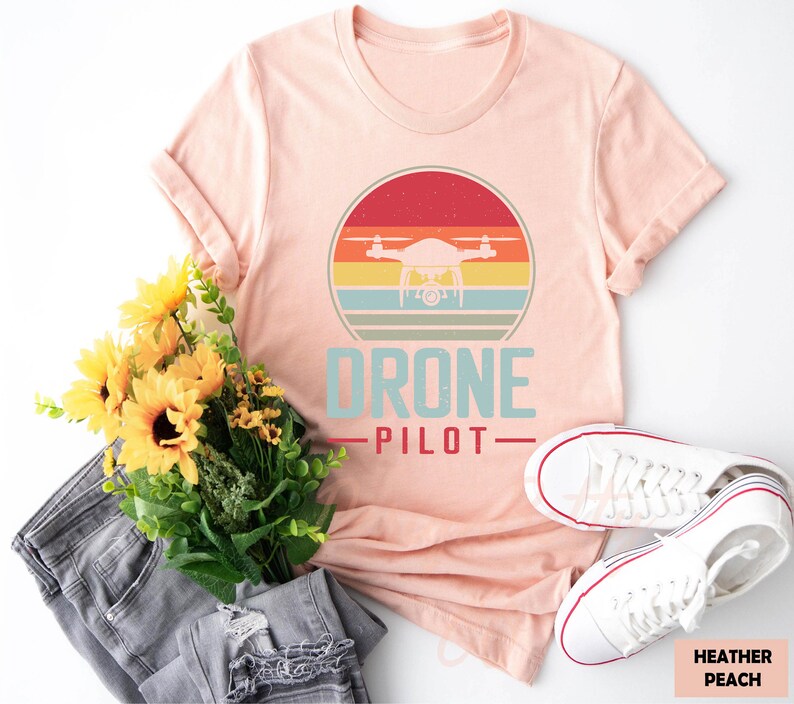 a t - shirt that says drone pilot next to a bouquet of sunflowers