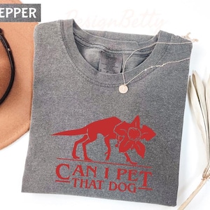 a gray t-shirt with a red graphic design, a necklace, a hat, and a fan, all arranged on a white background.