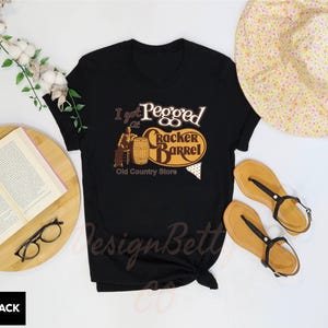 a black t - shirt with a picture of a barrel and a book