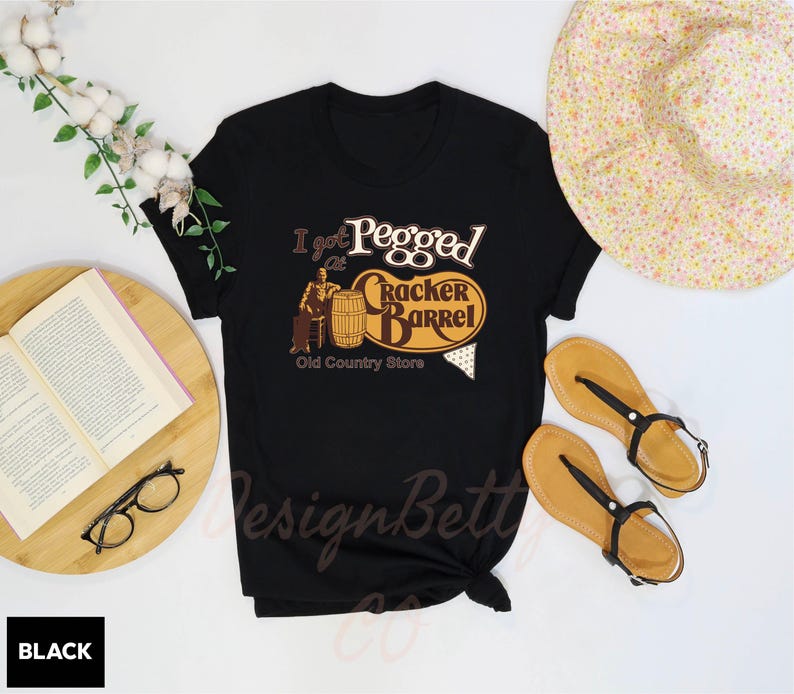 a black t - shirt with a picture of a barrel and a book